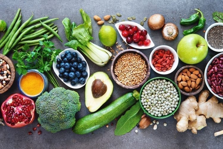What is Whole Food Plant-Based Diet? Healthy food selection with fruits, vegetables, seeds, superfood, cereals on grey background.