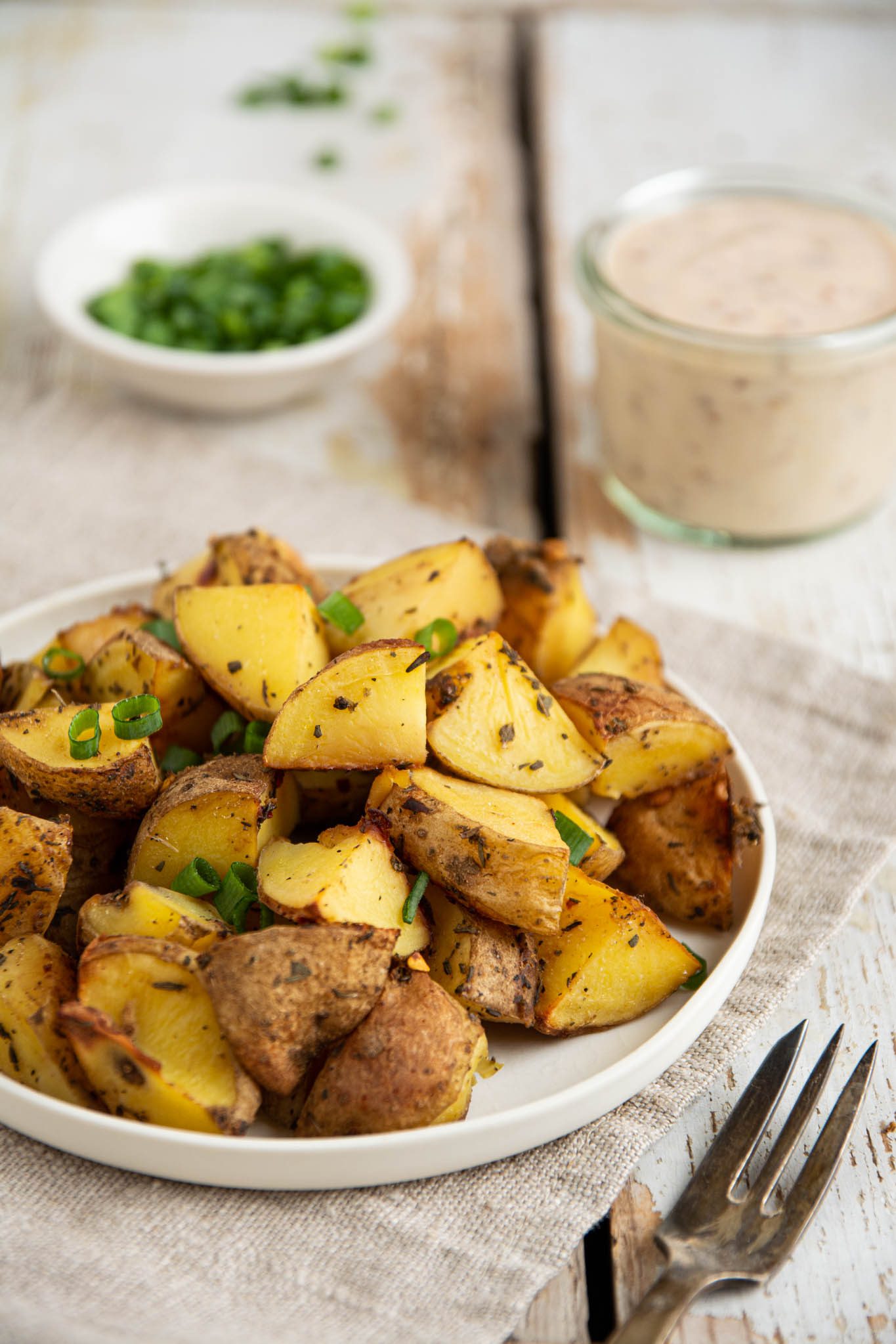 Learn how to make an herby baked potato recipe in the oven without oil or butter. Those baked potatoes are easy to make and pair perfectly with homemade mustardy yogurt dipping sauce.